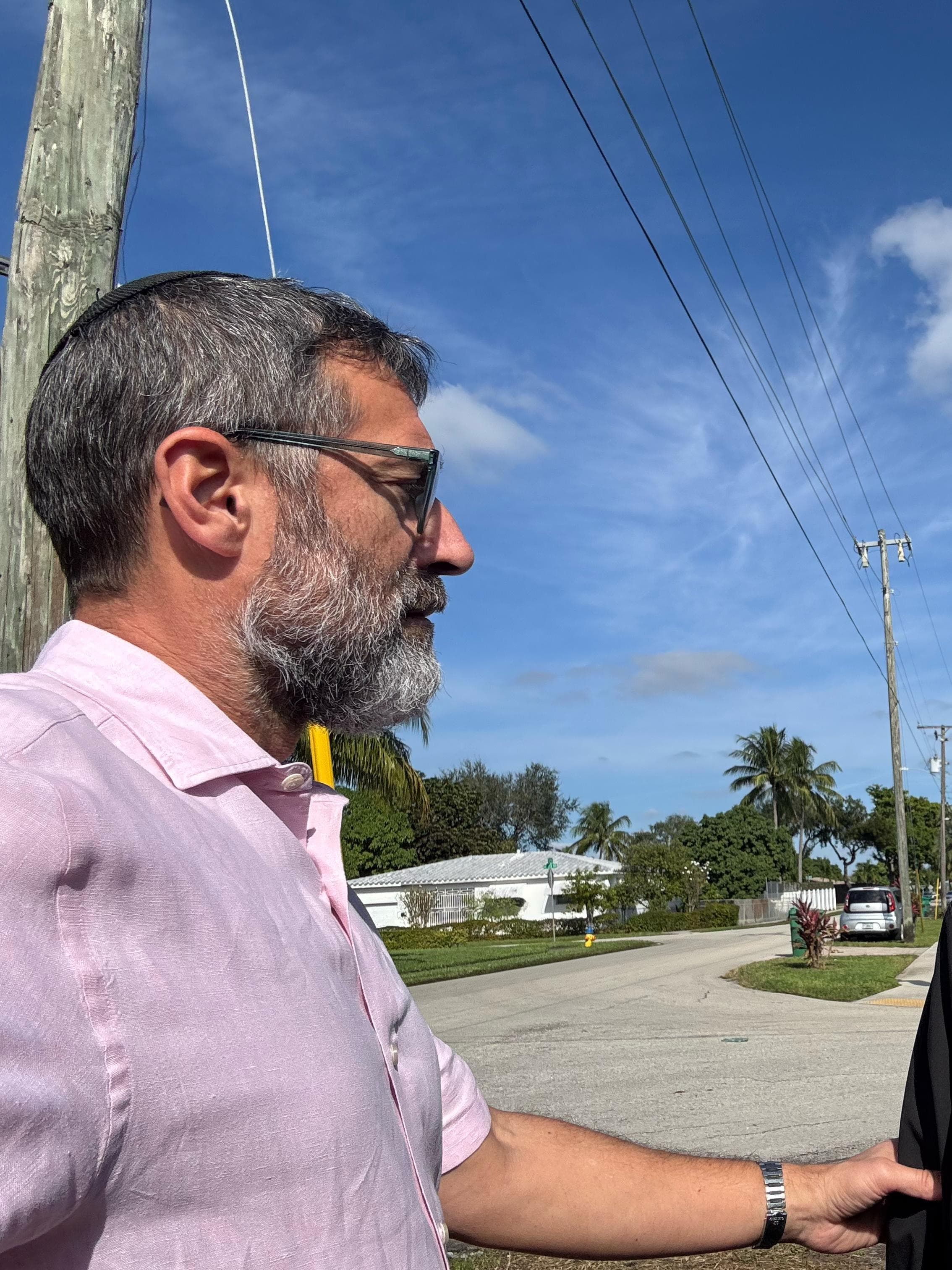 Chaim Backman walking a client along a residential street, one arm extended to steady them