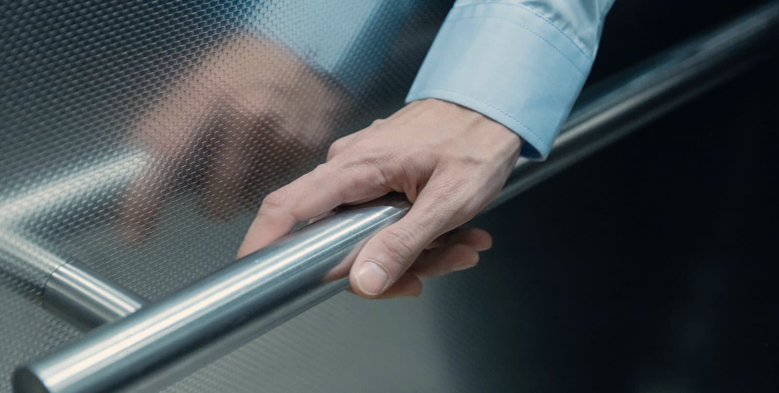 A hand resting on a polished steel grab rail