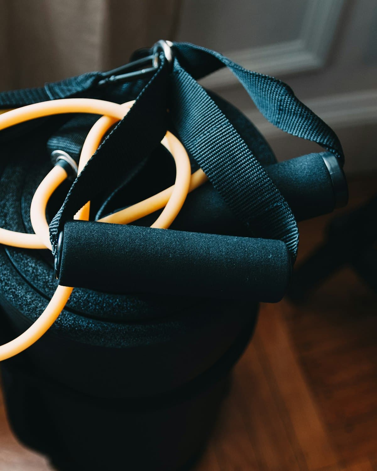 A resistance band with foam handles, coiled on top of home exercise gear
